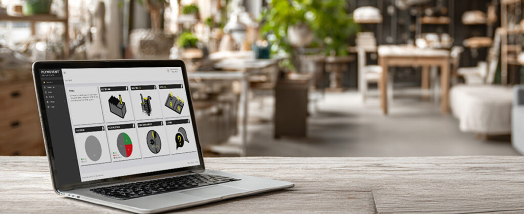 A laptop displaying the Plymovent website, set on a table in a modern, bright office or showroom environment.
